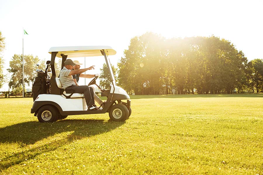 Specialized Business Insurance - Two Friends Driving Around a Golf Course in a Golf Cart